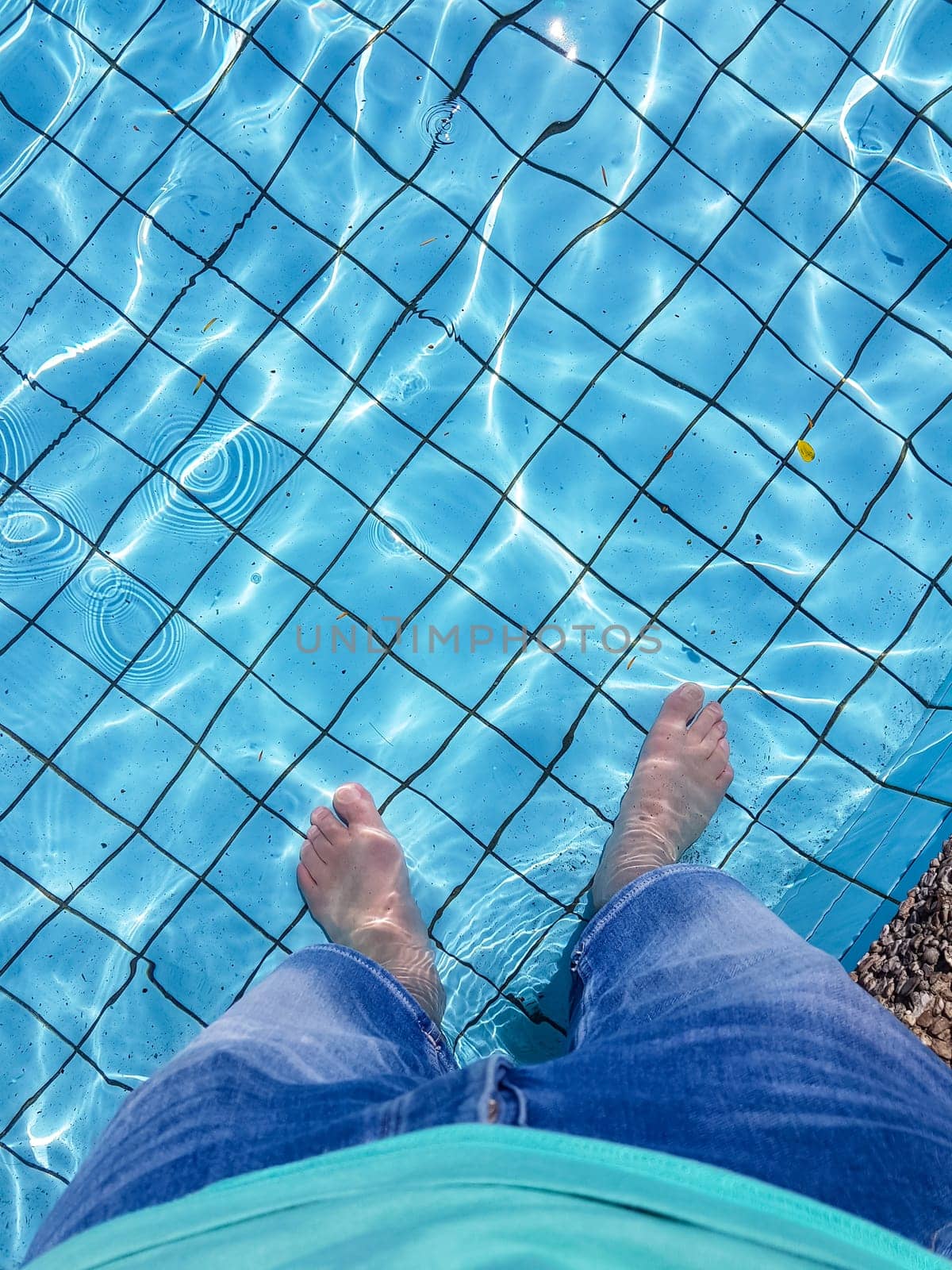 Male feet with skin tanning dipping in a swimming pool