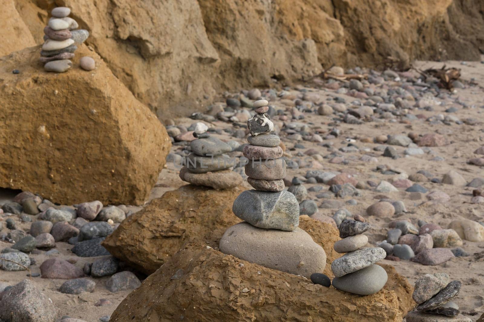 Stones stacked on top of each other on the beach in the background the cliff