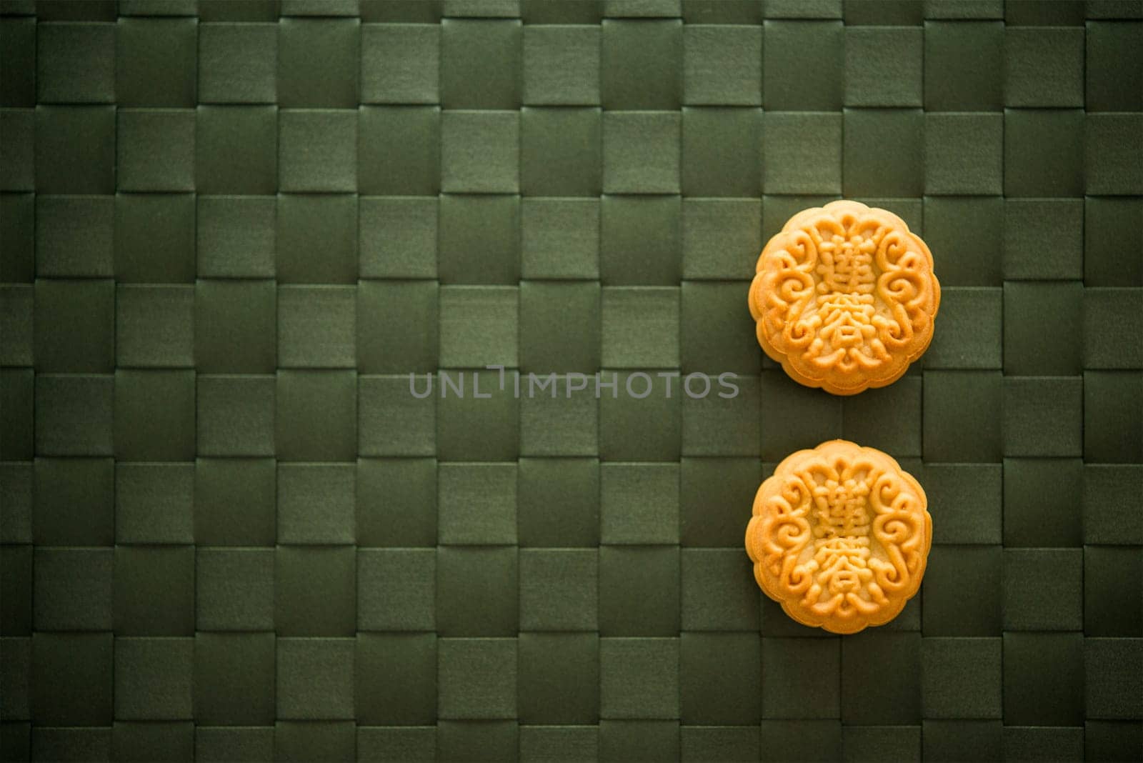 Traditional pastry moon cakes is eaten during the Mid-Autumn Festival. Flatlay table top view low light with copy space. The Chinese character represent "lotus paste""."