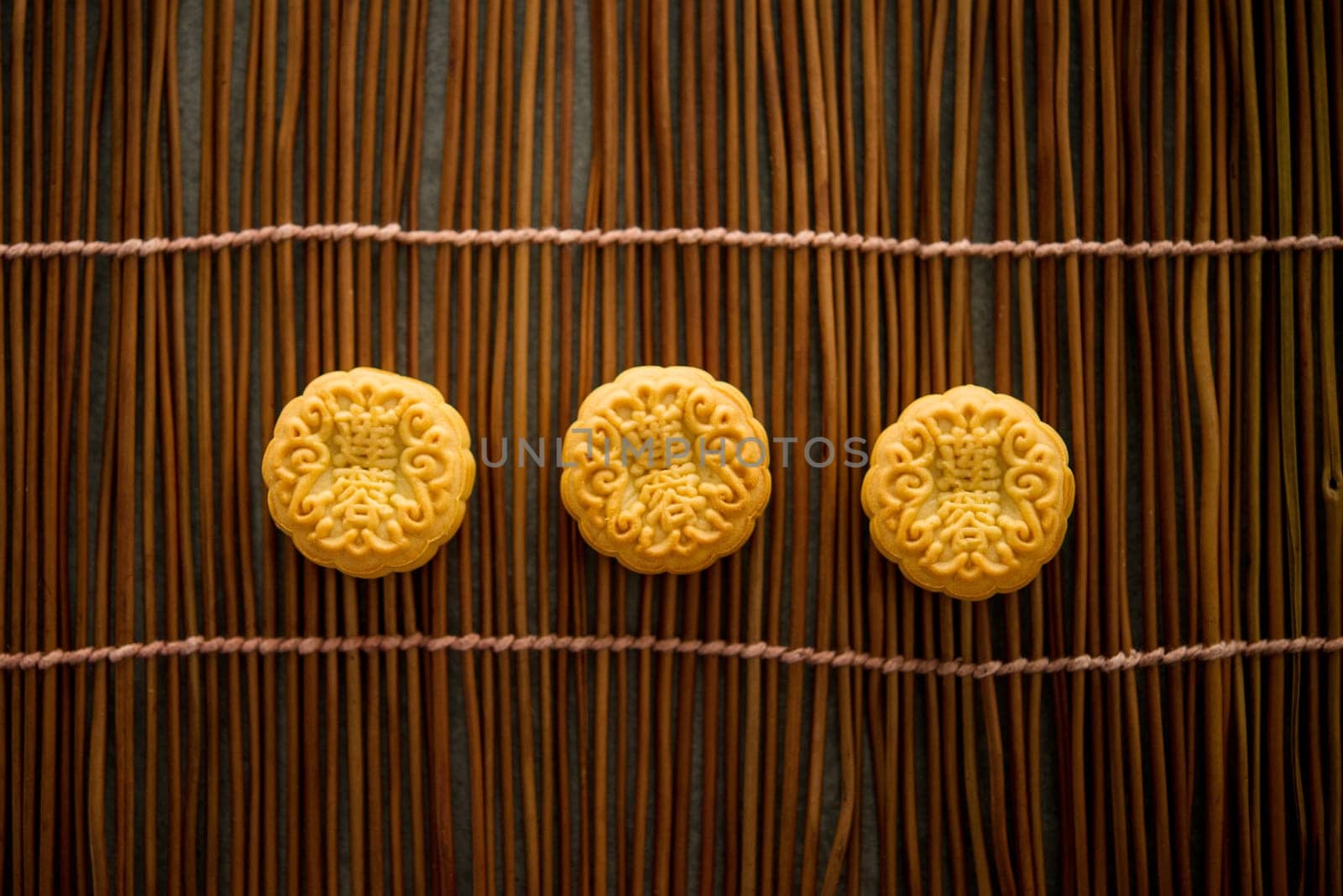 Traditional baked pastry mooncakes is eaten during the Mid-Autumn Festival. Flatlay on table, top down view low light with copy space. The Chinese character represent "lotus paste""."
