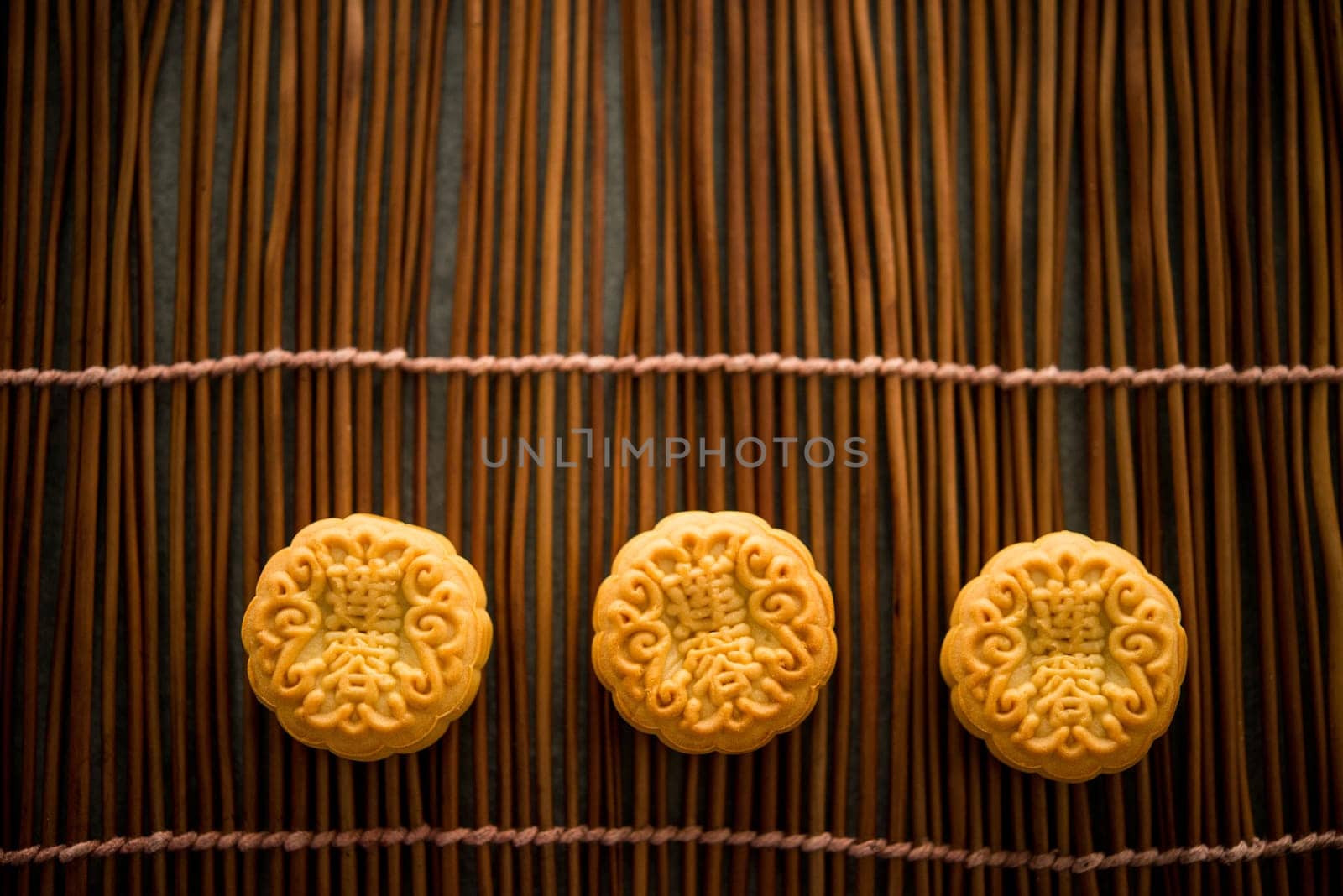 Traditional pastry moon cakes is eaten during the Mid-Autumn Festival. Flatlay on table, top down view low light with copy space. The Chinese character represent "lotus paste""."