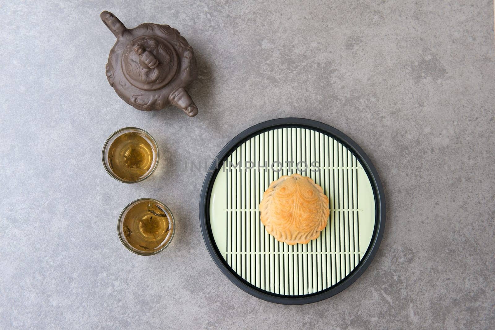 Traditional mooncakes is offered to friends or family during Mid-Autumn Festival. Flatlay on table top down view grey background with copy space. The Chinese character represent "lotus paste""."