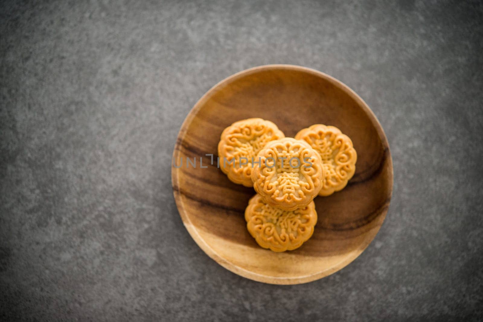 Traditional baked moon cakes is offered to friends or family during Mid-Autumn Festival. Flatlay on table top down view dark background with copy space. The Chinese character represent "lotus paste""."