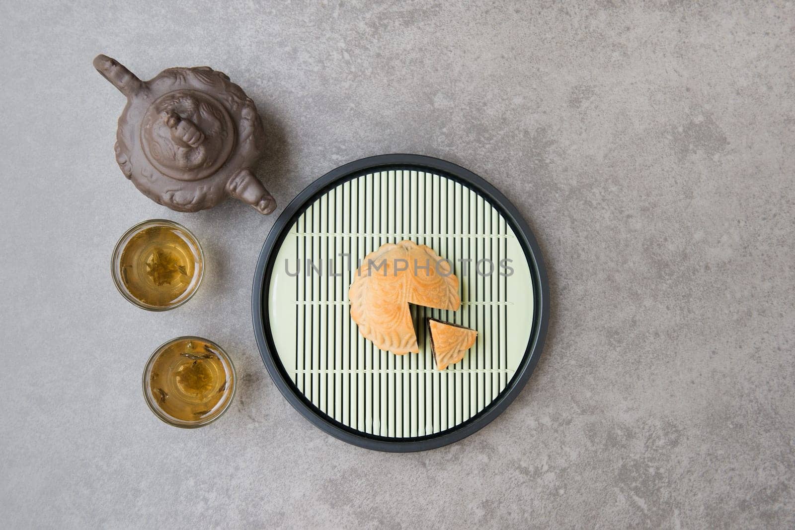 Traditional baked moon cakes is offered to friends or family during Mid-Autumn Festival. Flatlay on table top down view grey background with copy space. The Chinese character represent "lotus paste""."