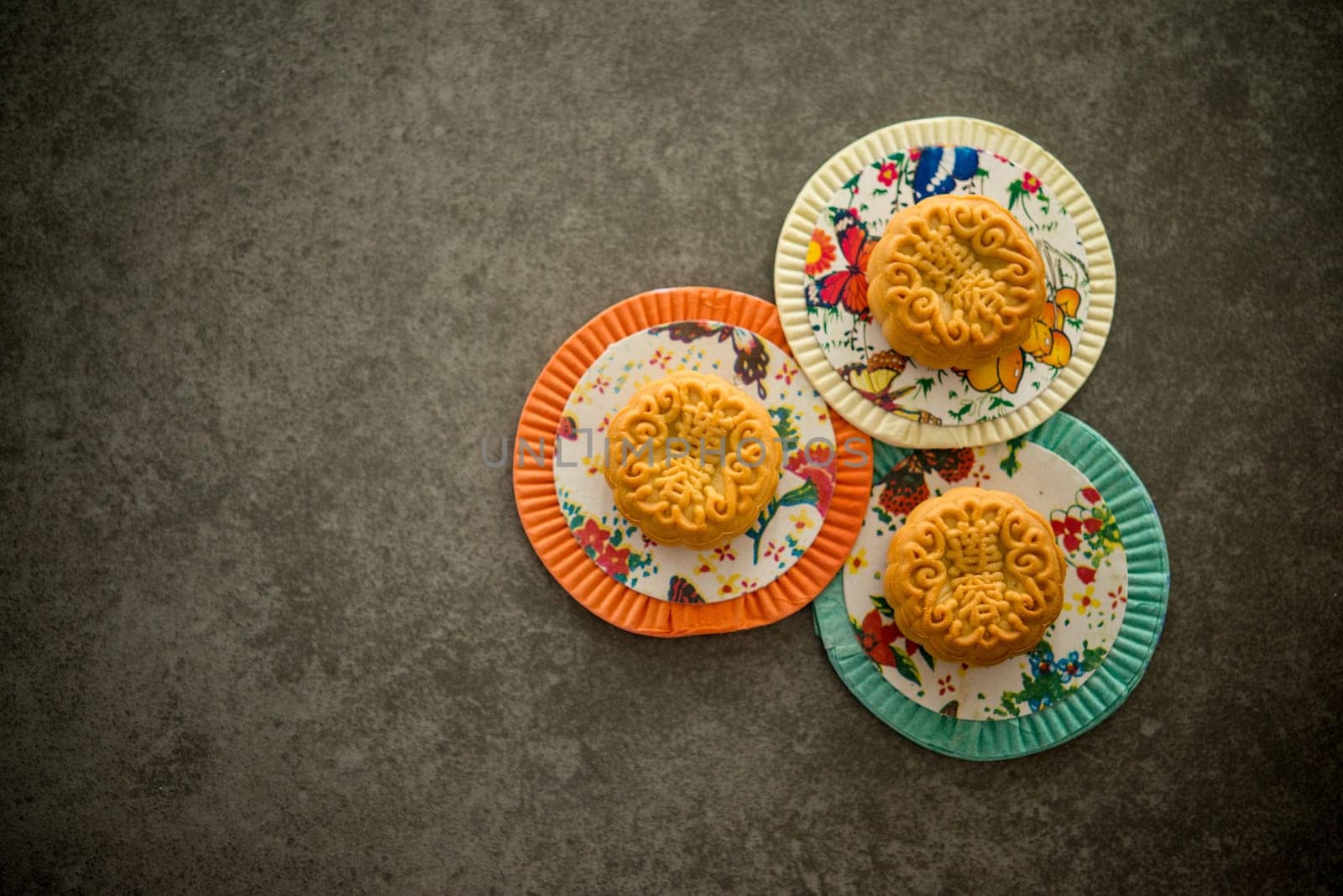 Traditional baked pastry moon cakes is eaten during the Mid-Autumn Festival. Flatlay on table, top down view low light with copy space. The Chinese character represent "lotus paste""."