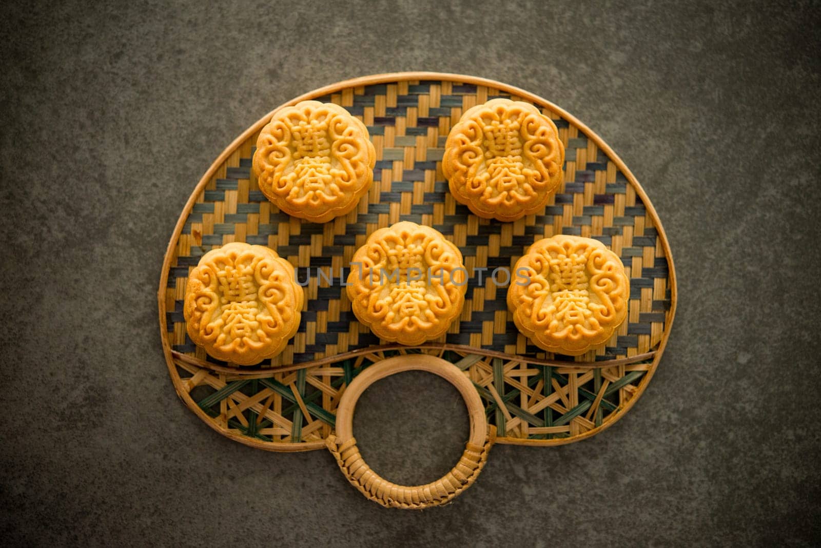 Traditional baked mooncakes is offered to friends or family during Mid-Autumn Festival. Flatlay on table, top down view dark background. The Chinese character represent "lotus paste""."