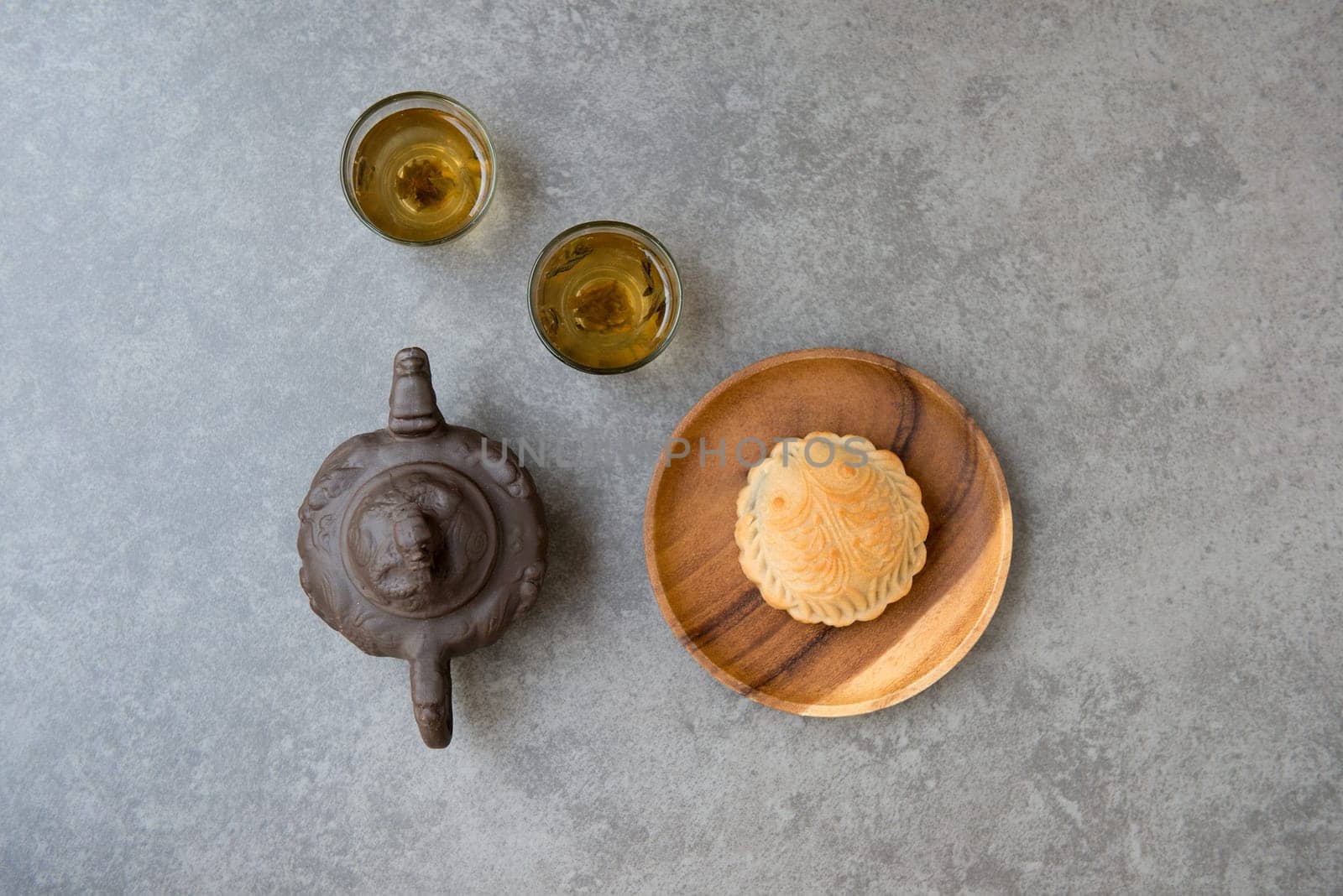 Traditional baked mooncakes is offered to friends or family during Mid-Autumn Festival. Flatlay on table top down view grey background with copy space. The Chinese character represent "lotus paste""."