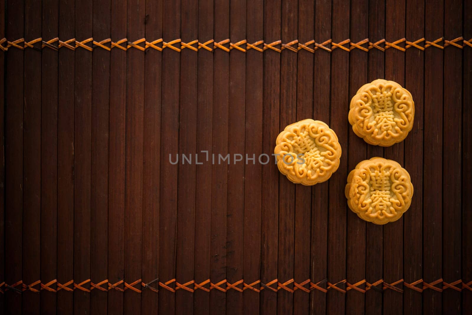 Traditional baked mooncakes is offered to friends or family during Mid-Autumn Festival. Flatlay table top view low light background with copy space. The Chinese character represent "lotus paste""."