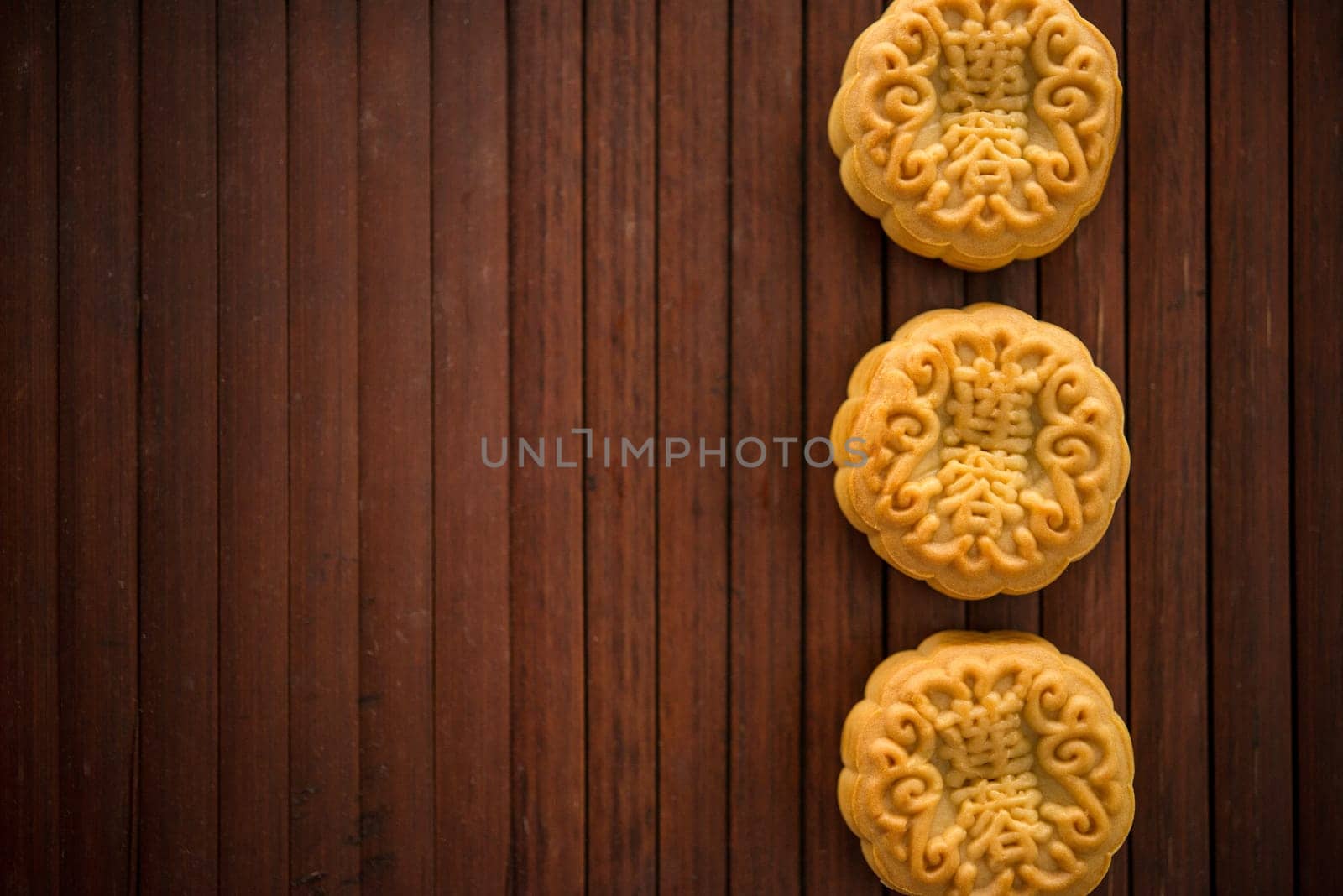 Traditional pastry mooncakes is offered to friends or family during Mid-Autumn Festival. Flatlay table top view low light with copy space. The Chinese characte represent "lotus paste""."