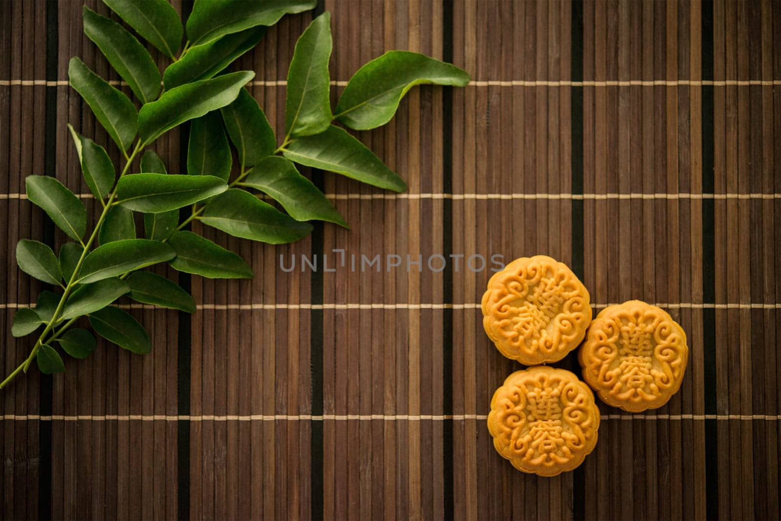 Traditional pastry moon cakes is eaten during the Mid-Autumn Festival. Flatlay on table, top down view dark light with copy space. The Chinese character represent "lotus paste""."