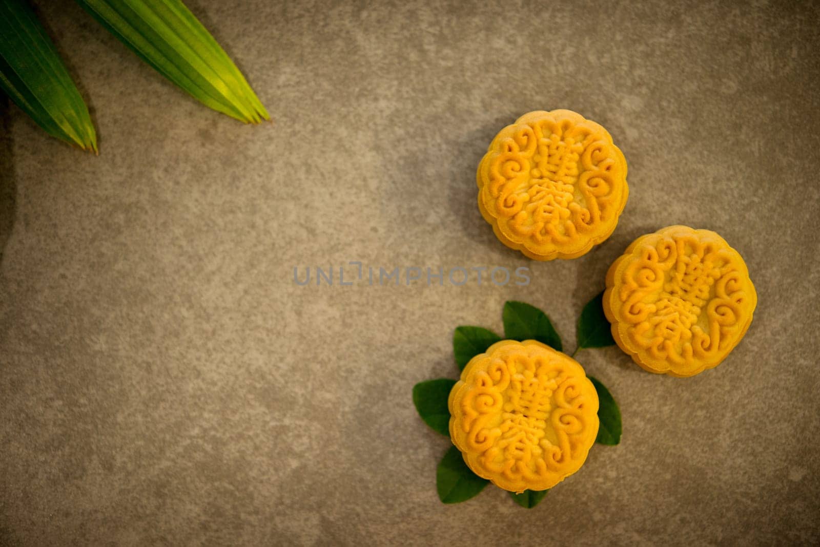 Mooncakes is traditional pastry eaten during the Mid-Autumn Festival. Flatlay on table, top down view low light with copy space. The Chinese character represent "lotus paste""."
