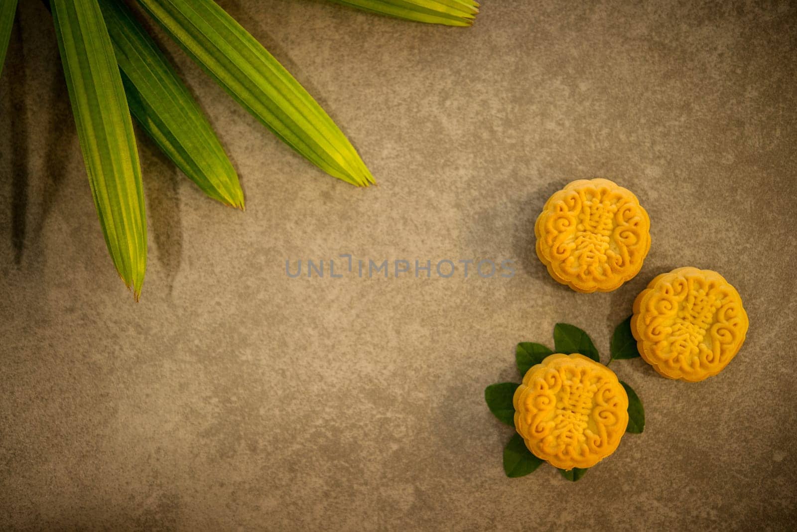 Moon cakes is traditional pastry eaten during the Mid-Autumn Festival. Flatlay on table, top down view low light with copy space. The Chinese character represent "lotus paste""."
