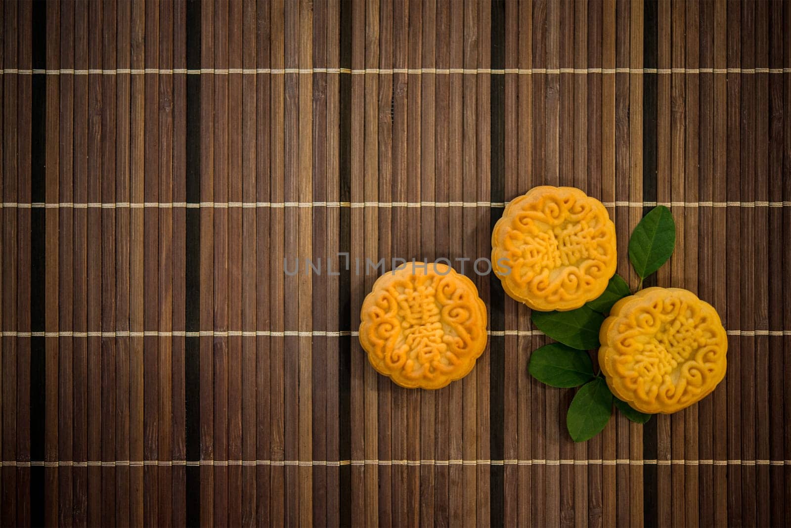 Moon cakes is traditional pastry eaten during the Mid-Autumn Festival. Flatlay on table, top down view dark light with copy space. The Chinese character represent "lotus paste""."