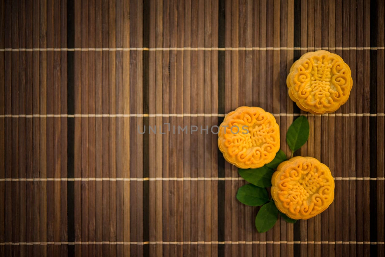 Mooncakes is traditional pastry eaten during the Mid-Autumn Festival. Flatlay on table, top down view dark light with copy space. The Chinese character represent "lotus paste""."