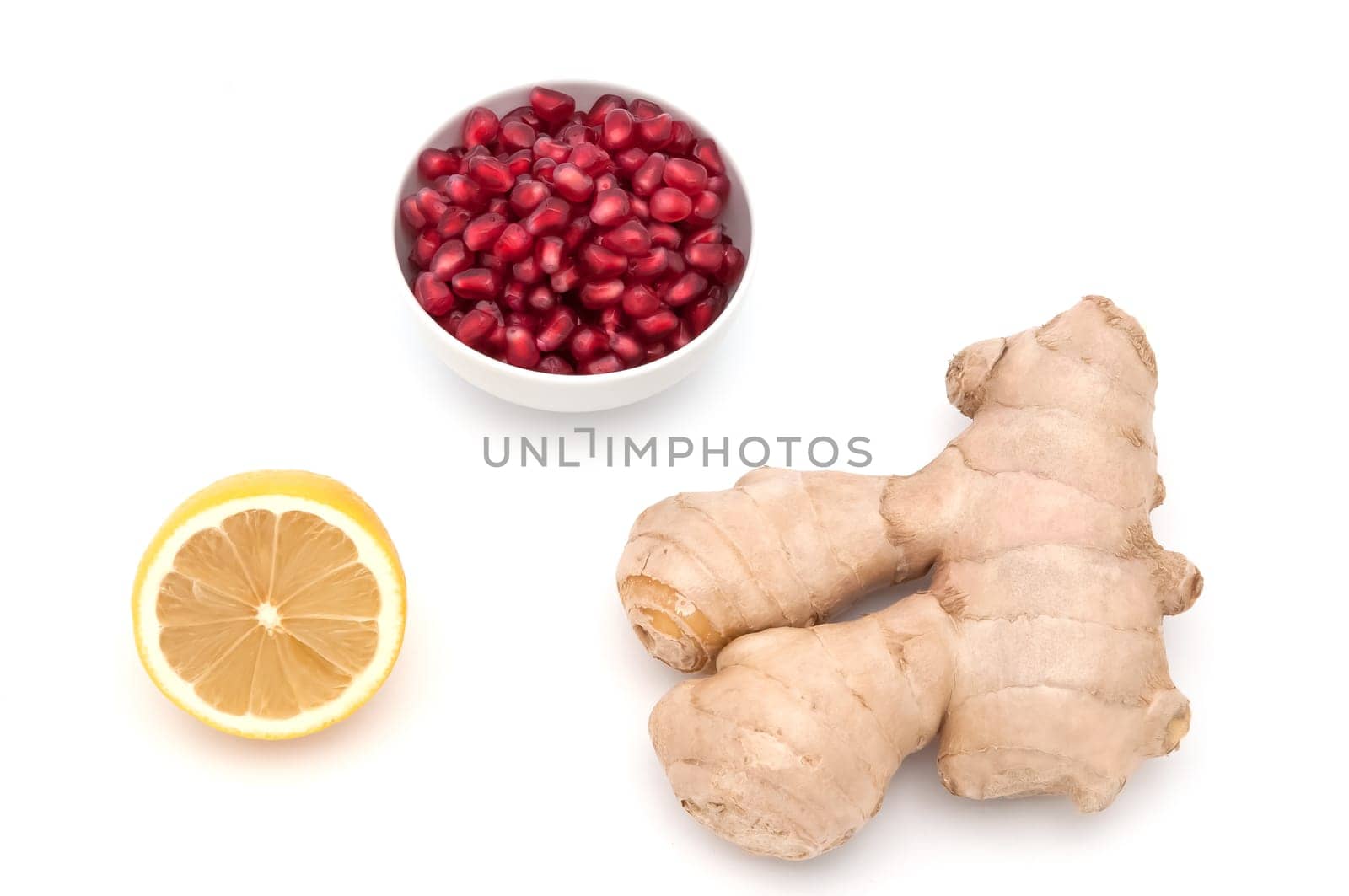 A ceramics cup of pomegranate seeds, ginger, lemon on a white background.