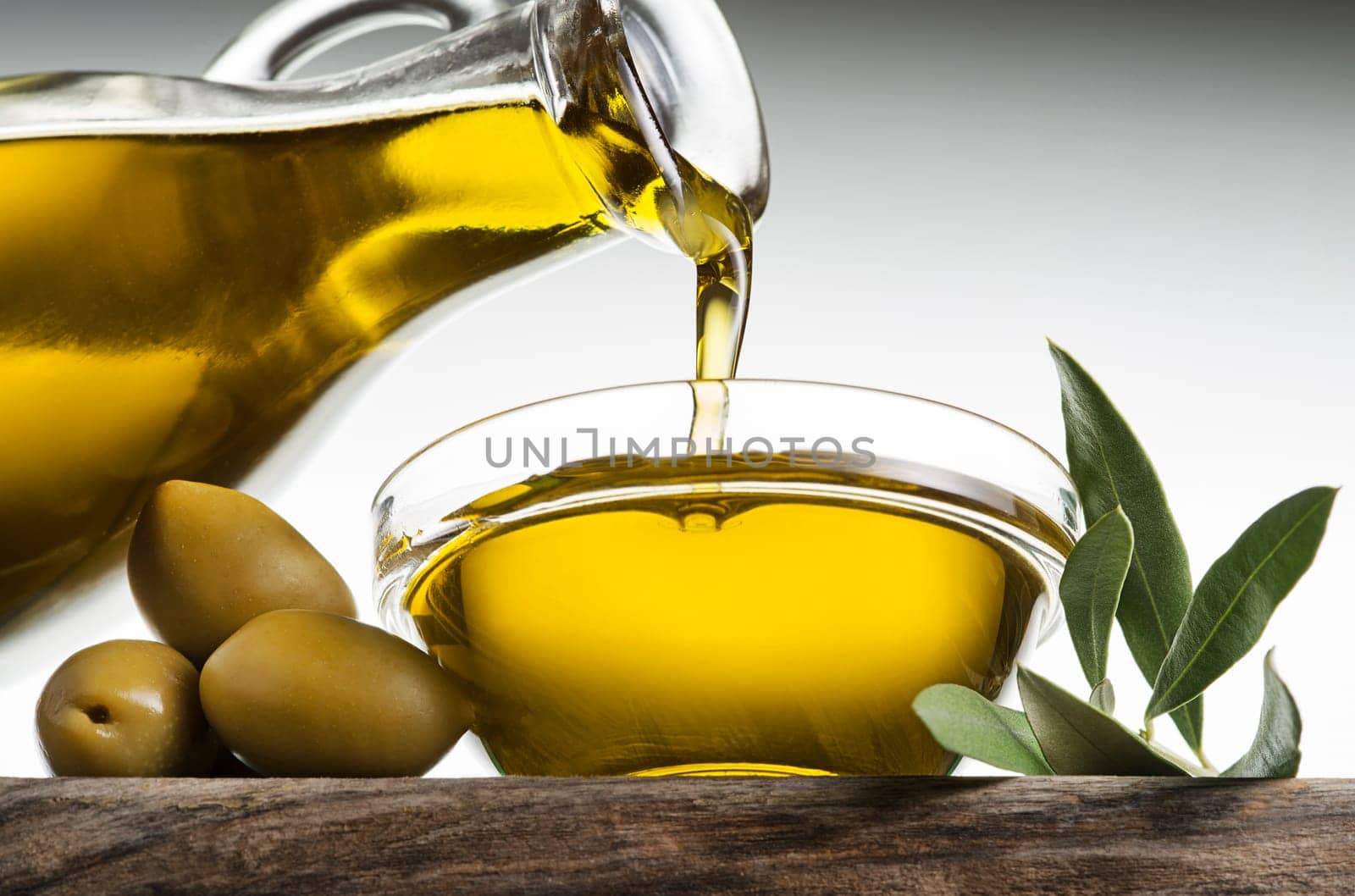 Bottle of virgin olive oil pouring in a bowl close up