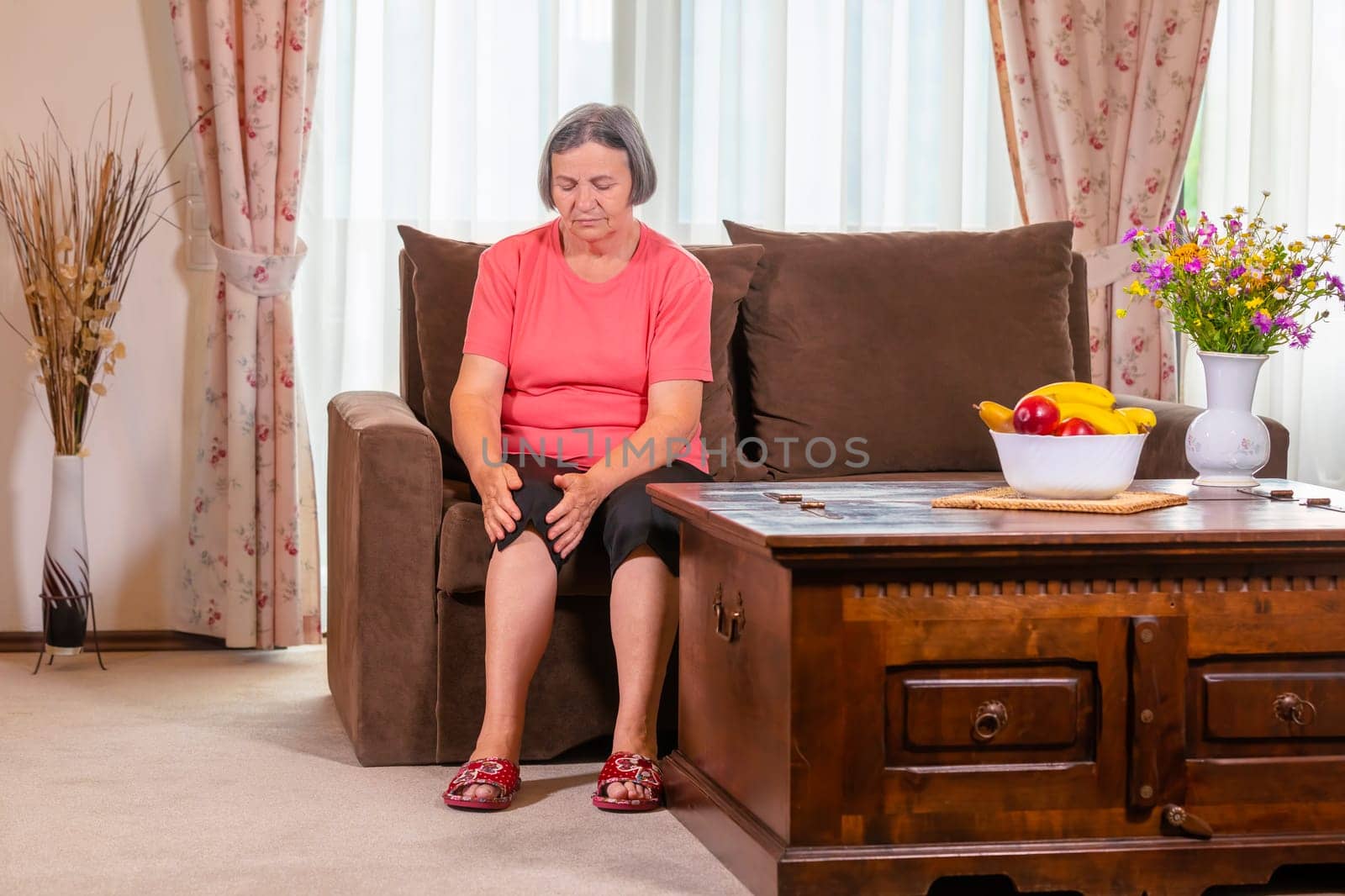 Elderly woman suffering from pain in knee at home. Old age health problem and people concept senior woman suffering from pain in leg at home.