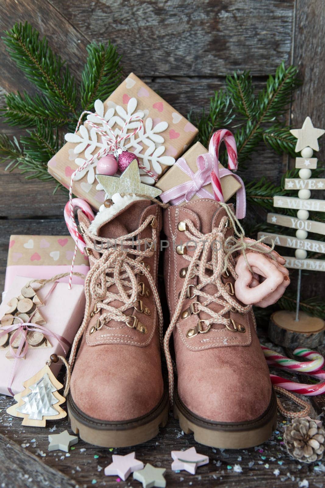 Rustic boots with christmas presents on wooden background