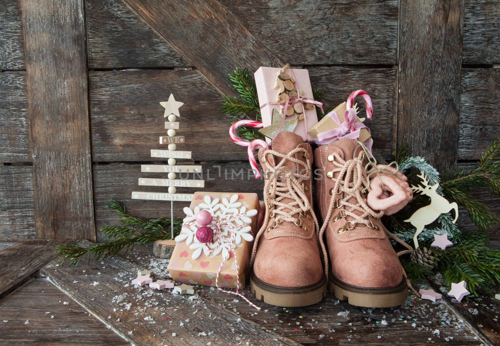 Rustic boots with christmas presents on wooden background