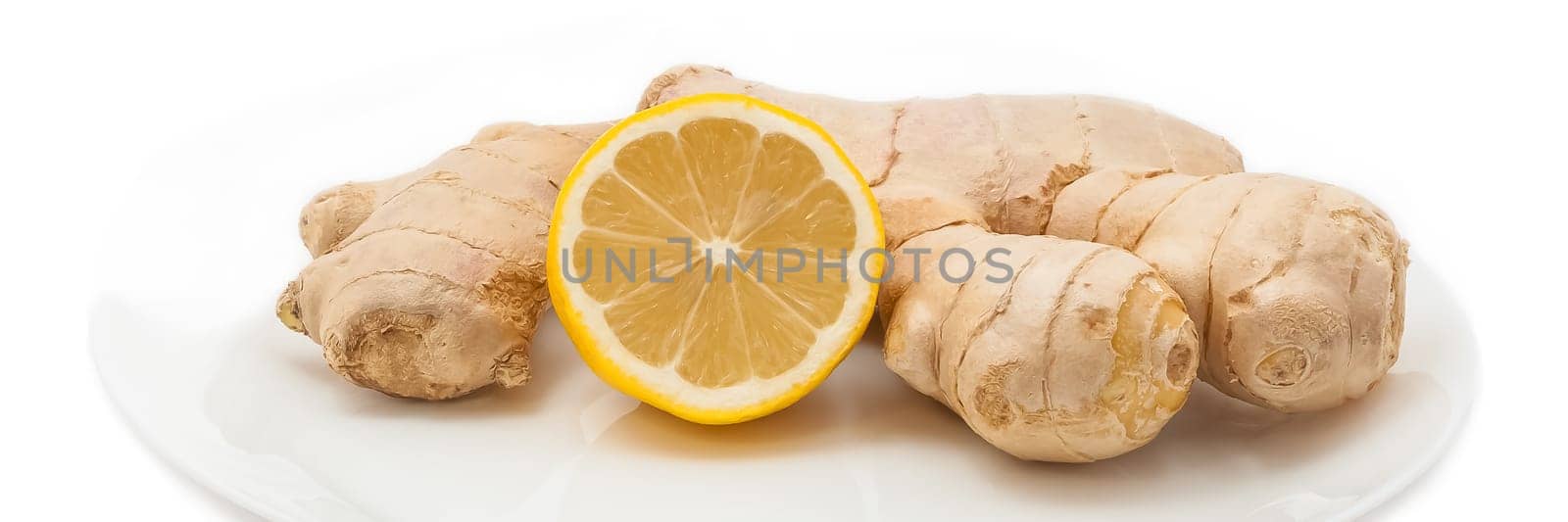 Fresh juicy yellow lemon with ginger on a white plate.