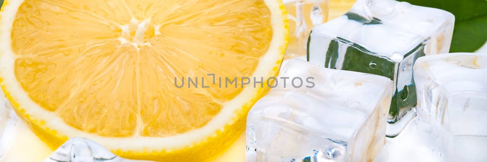 Half a juicy bright lemon and refreshing ice cubes close-up