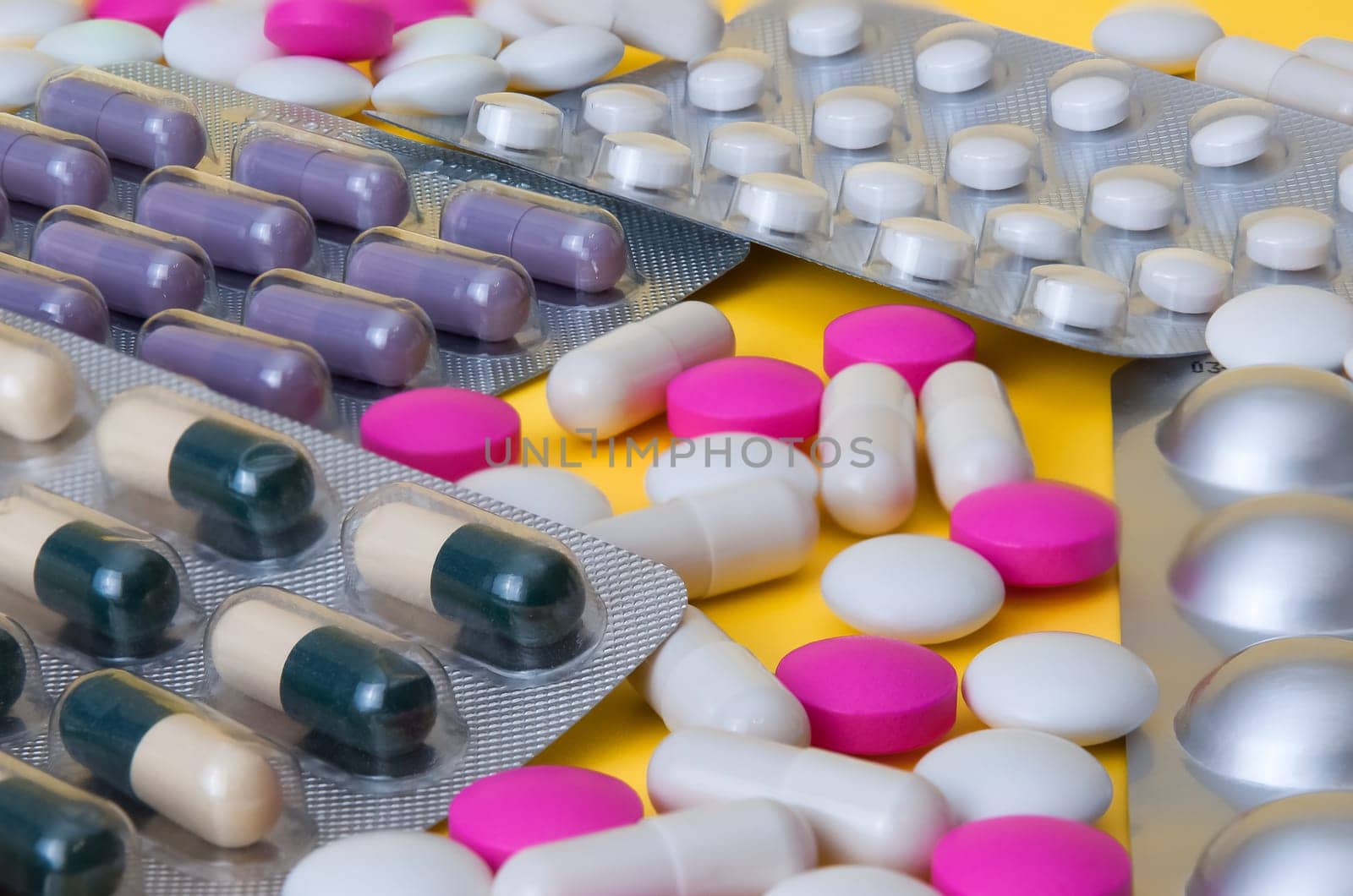White and pink tablets and blisters with colorful pills are scattered.