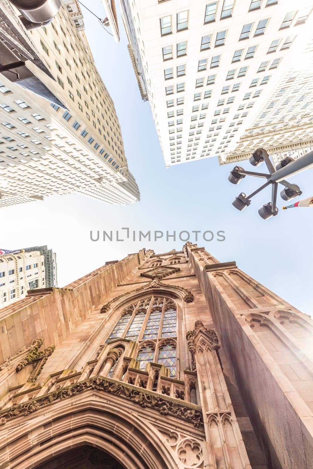 Wide angle upward view of Trinity Church at Broadway and Wall Street with surrounding skyscrapers, Lower Manhattan, New York City, USA.