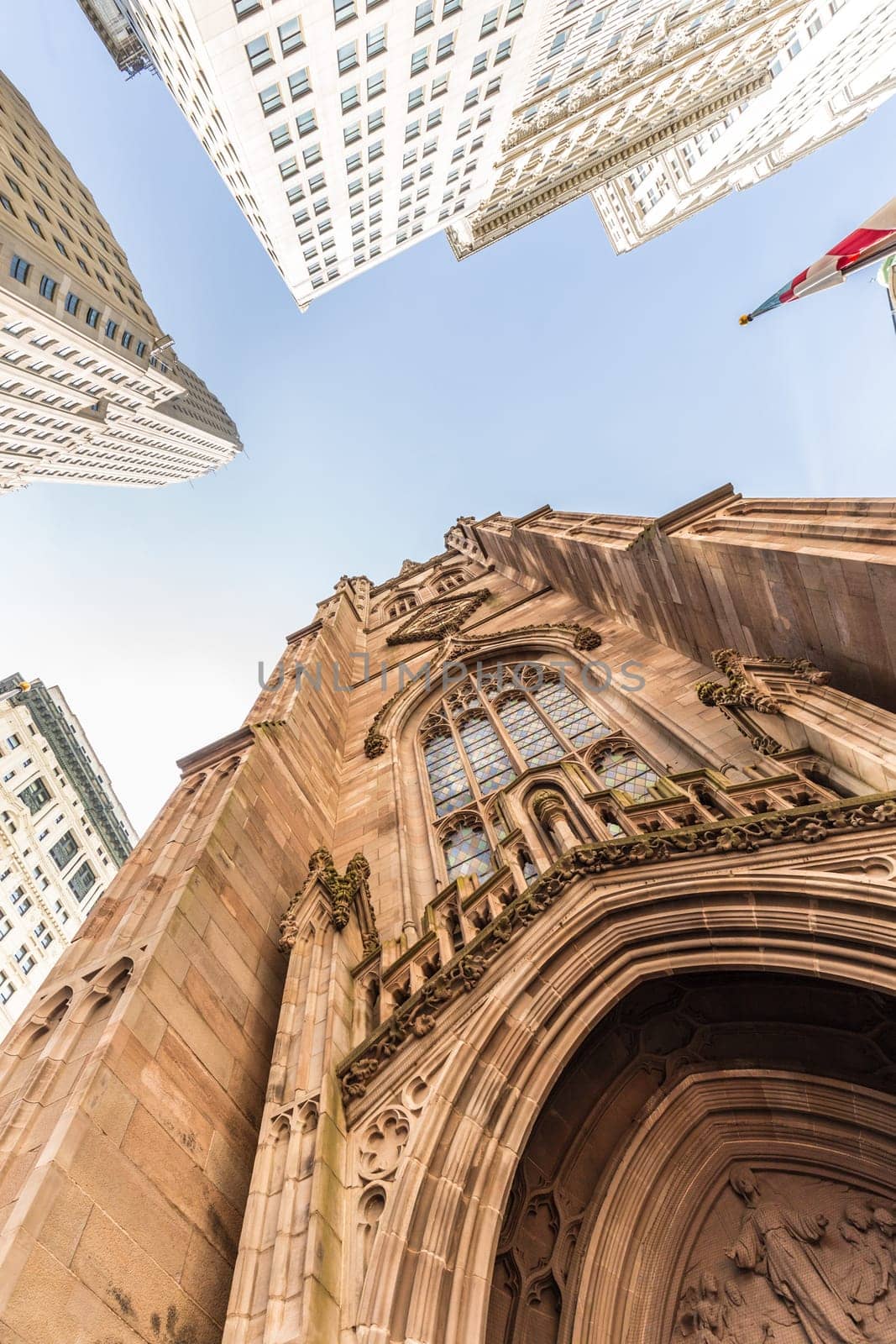 Wide angle upward view of Trinity Church at Broadway and Wall Street with surrounding skyscrapers, Lower Manhattan, New York City, USA.