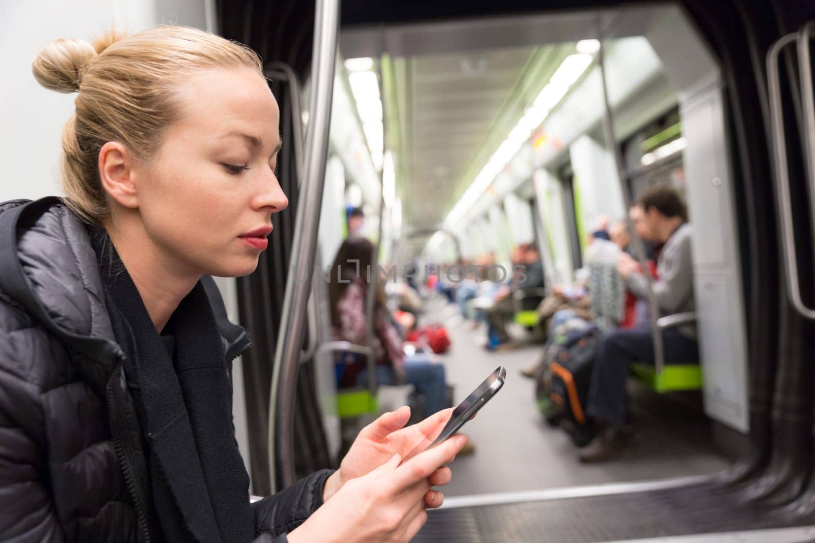 Young girl reading from mobile phone screen while traveling on metro. Wireless internet on public transport concept.