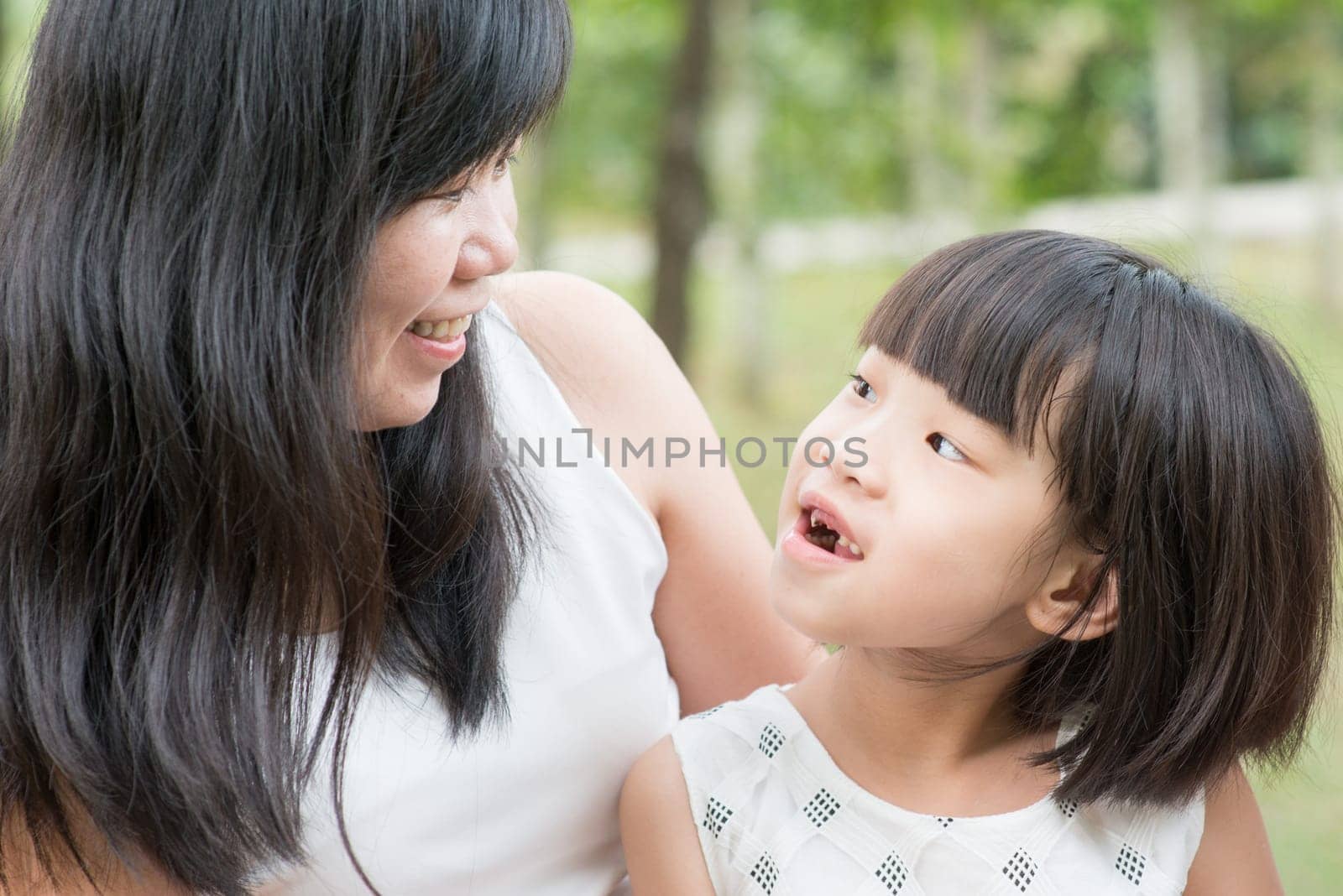 Happy mother and daughter bonding at green park. Asian family outdoors activity.