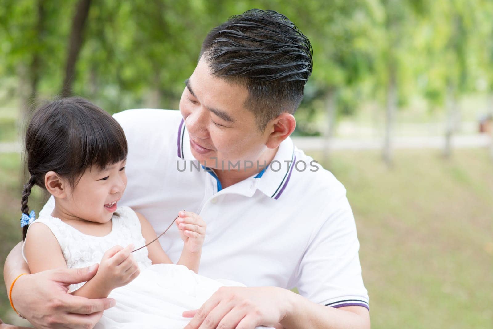 Happy father and daughter having fun at green park. Asian family outdoors activity.