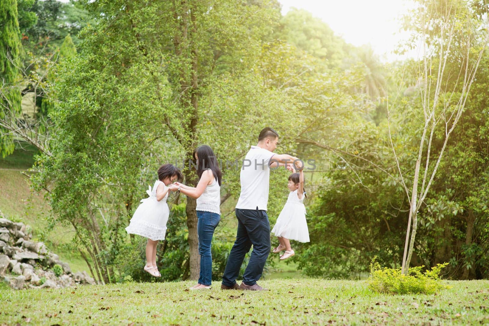Asian family outdoors. Parents and children playing at garden park.