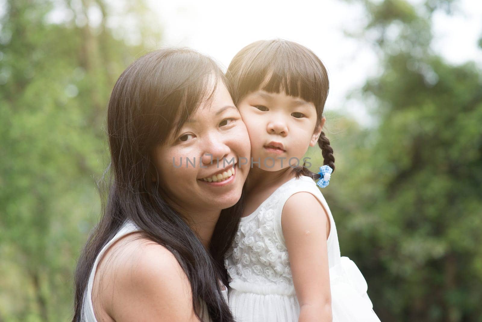 Asian family outdoors portrait. Mother and daughter enjoying nature at garden park.