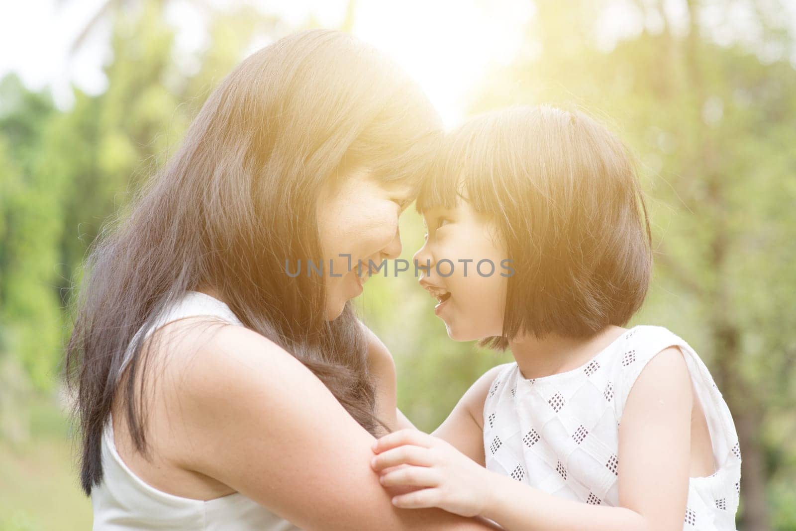 Asian family outdoors portrait. Mother and daughter having fun at garden park.