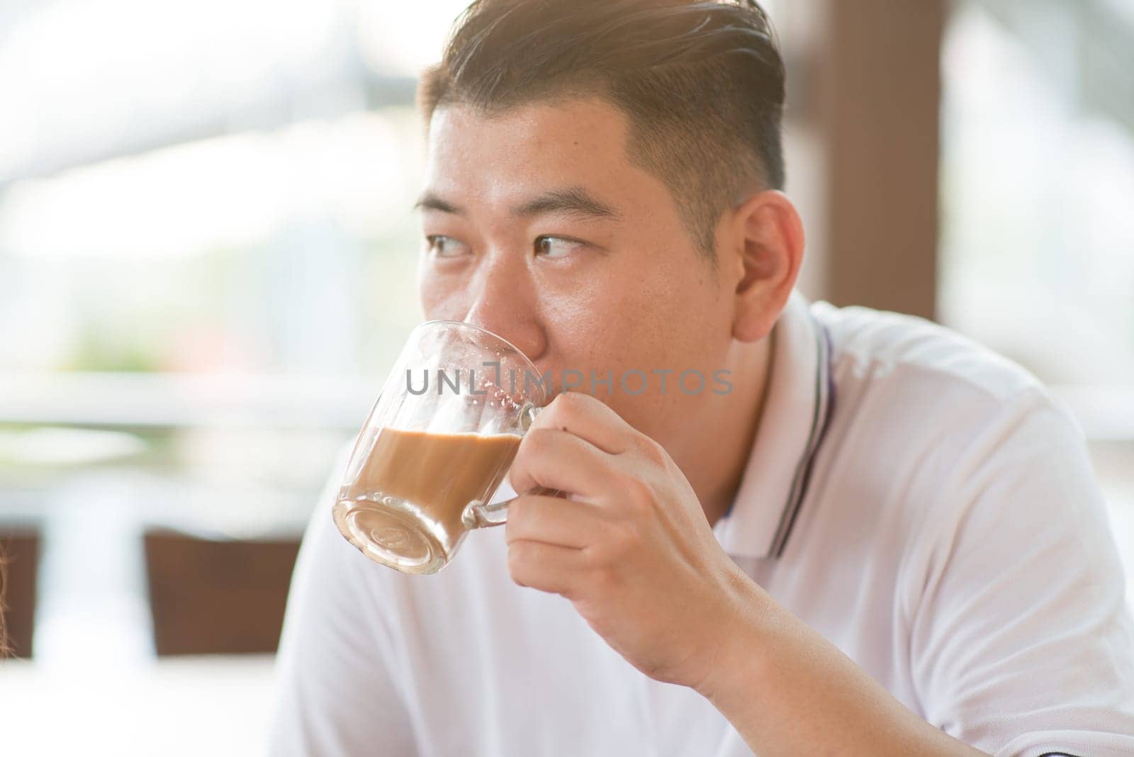 Asian mature man drinking milk tea at cafe. Outdoor lifestyle with natural light.