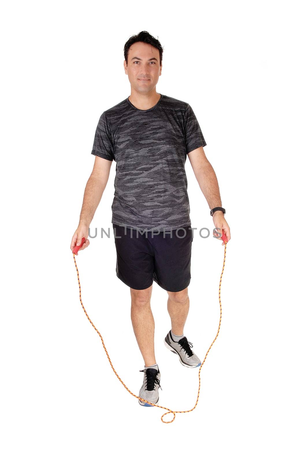 A young man standing in the studio exercising with his rope, in a sports.outfit, isolated for white background.