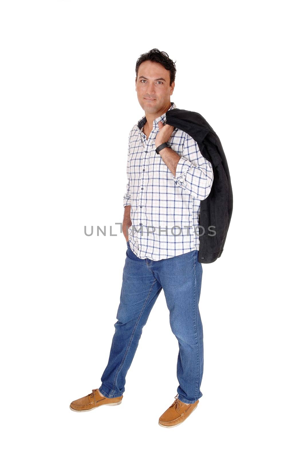 A tall handsome man standing in jeans with his black jacket over his.shoulder, looking into camera, isolated for white background.