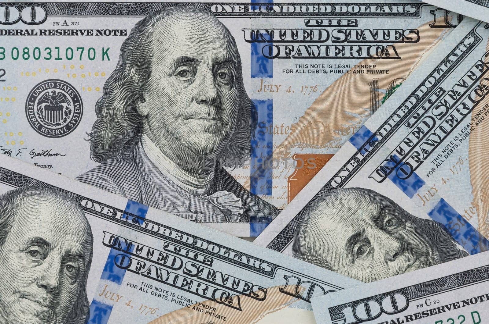 Denominations of one hundred US dollars. Spread out on the table. Not full visibility of notes.