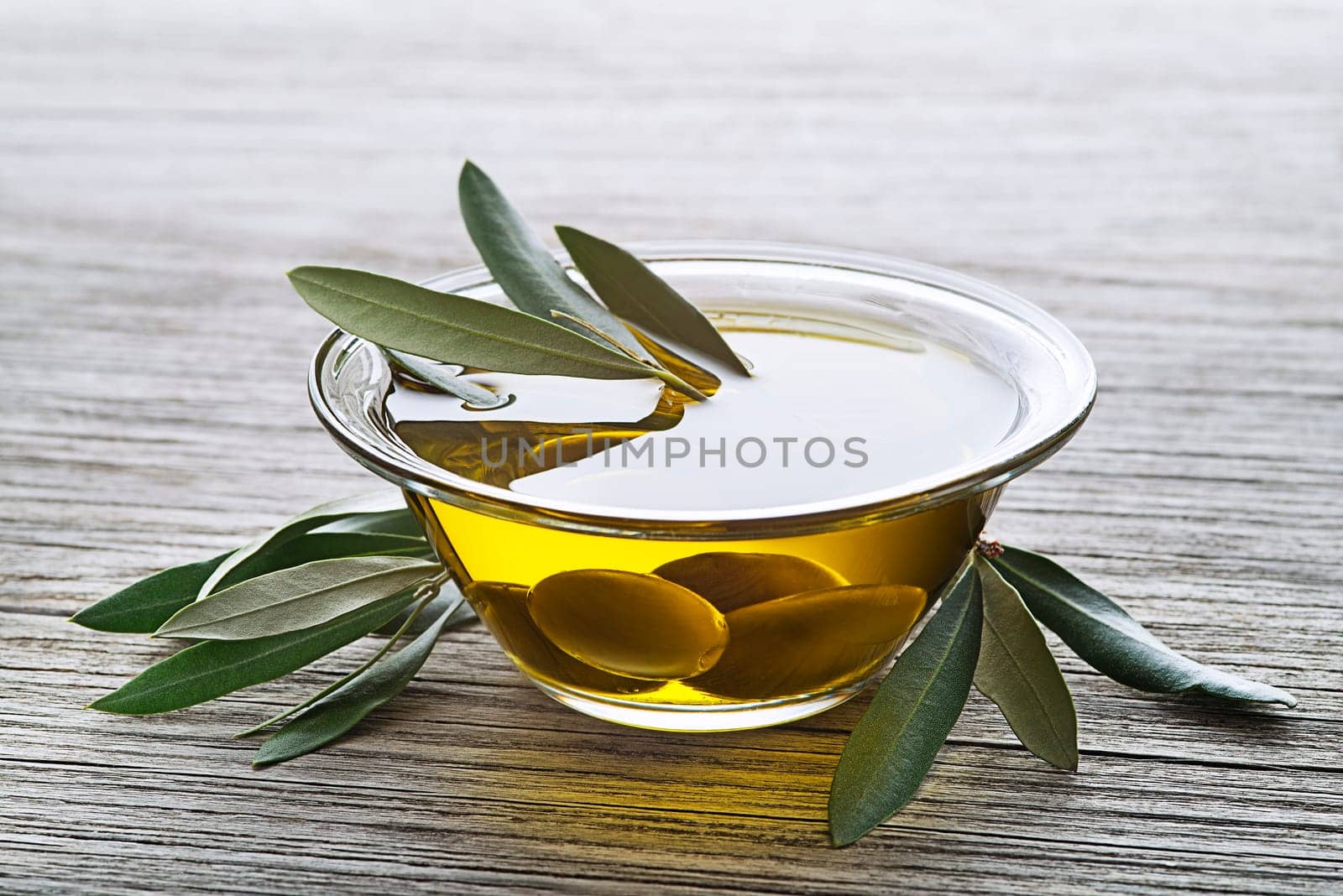 Bowl of virgin olive oil with olives close up