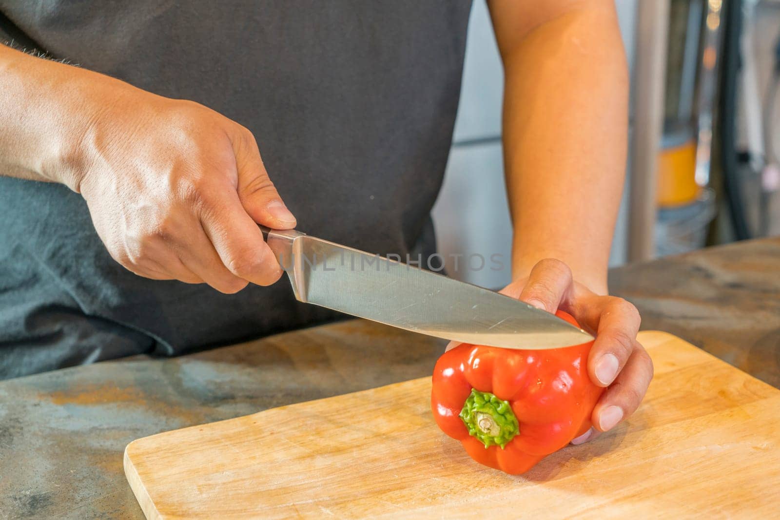 Chef cutting red bell pepper on wooden broad