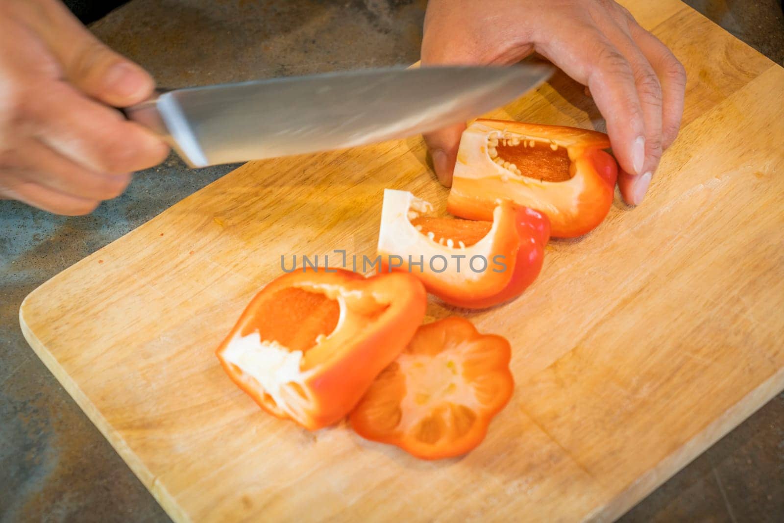 Chef cutting red bell pepper on wooden broad