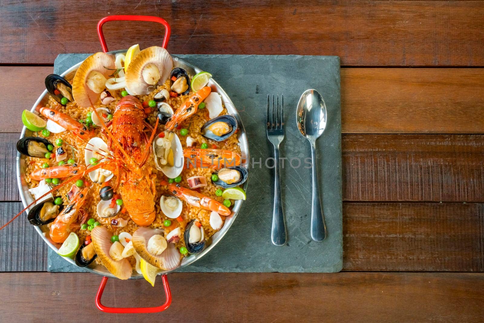 Gourmet seafood Valencia paella with fresh langoustine, clams, mussels and squid on savory saffron rice with prawn, scollops, mussels and lime slices, close up view