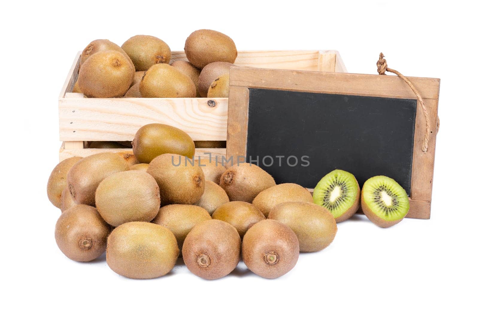 Wooden box filled with many ripe kiwi fruits and two half fruits and a old blank slate blackboard isolated on white background