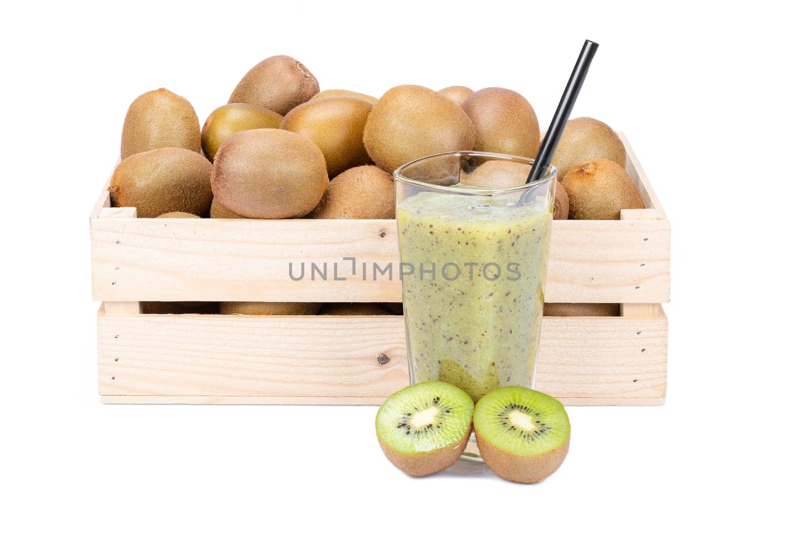 Wooden box with ripe kiwi fruits and a glass with fresh kiwi smoothie with a drinking straw isolated on white background