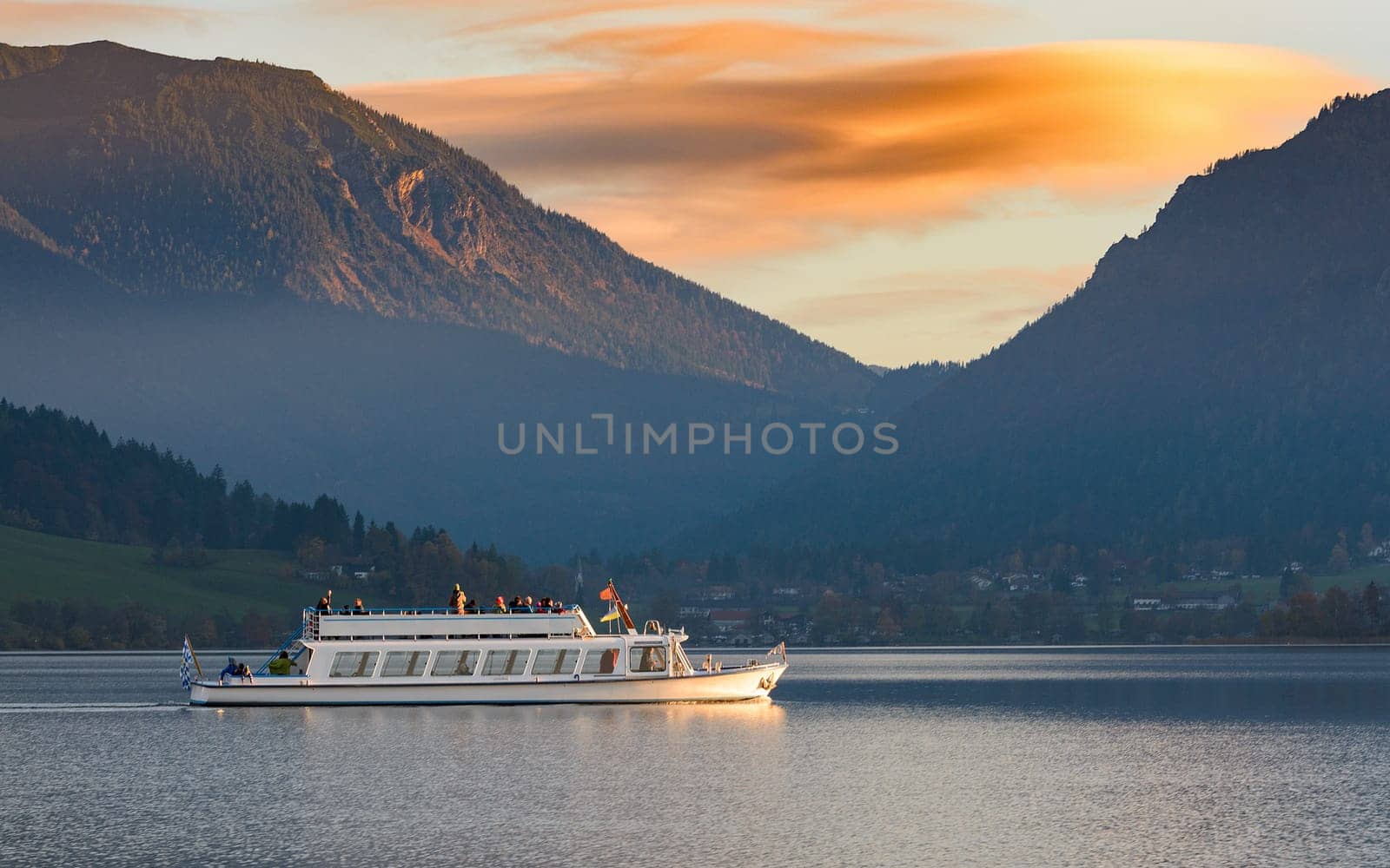 Pleasure boat on Alpine lake in Bavaria in the evening time before sunset