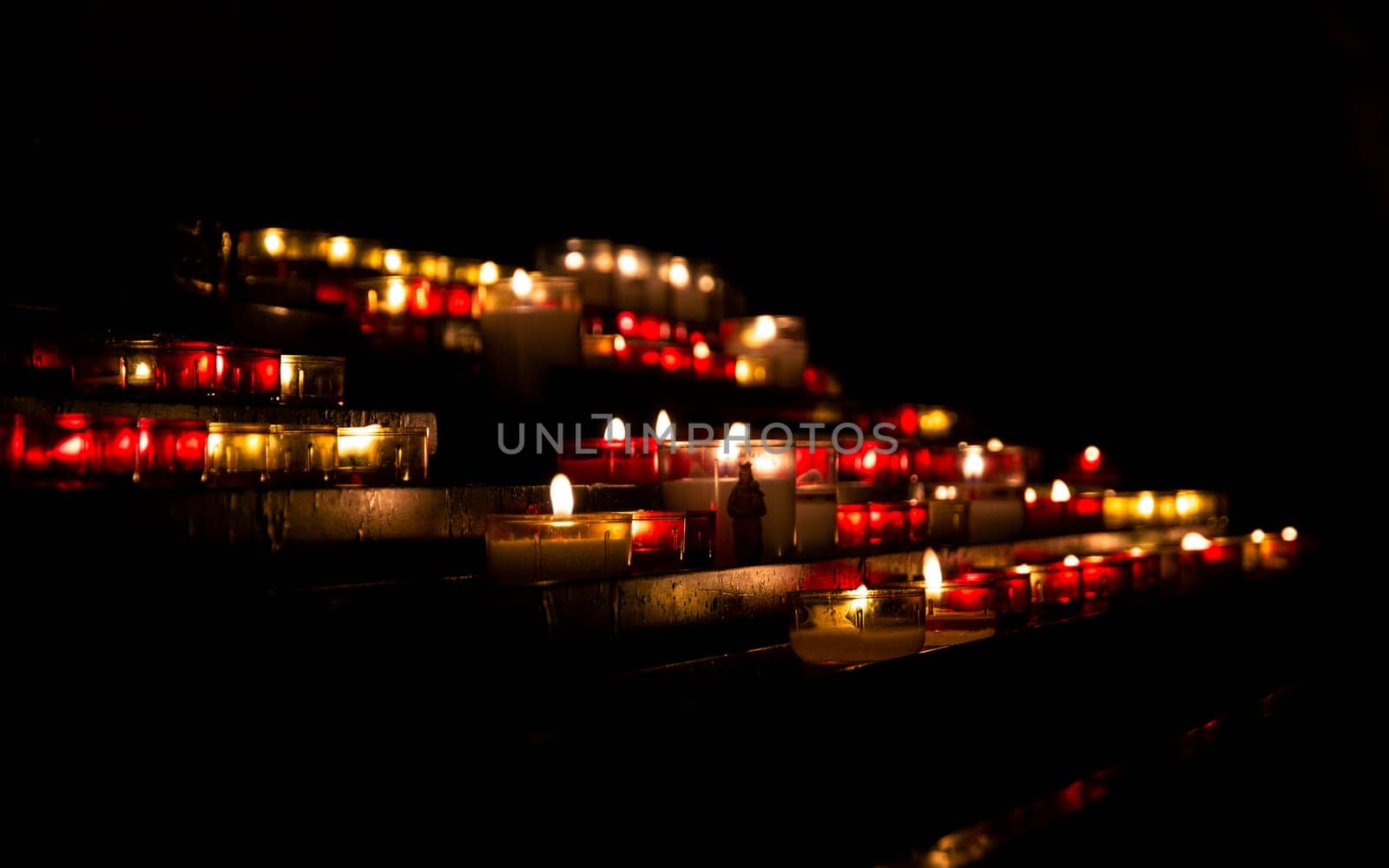 Bright lights of burning candles in the darkness of Christian church