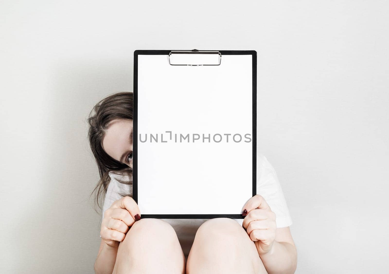 Woman holding clipboard with a blank paper. Blank paper poster with plenty of copy space in female hands.