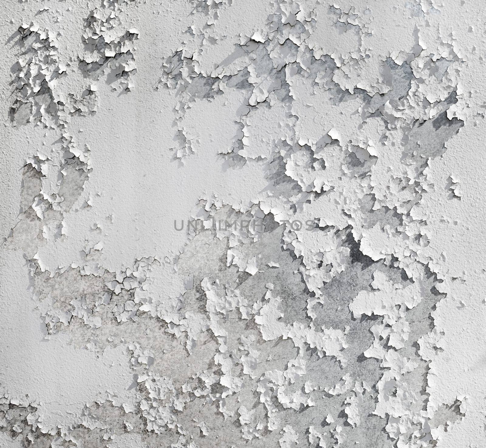 Old cracked wall with white peeling paint texture. Grunge background.