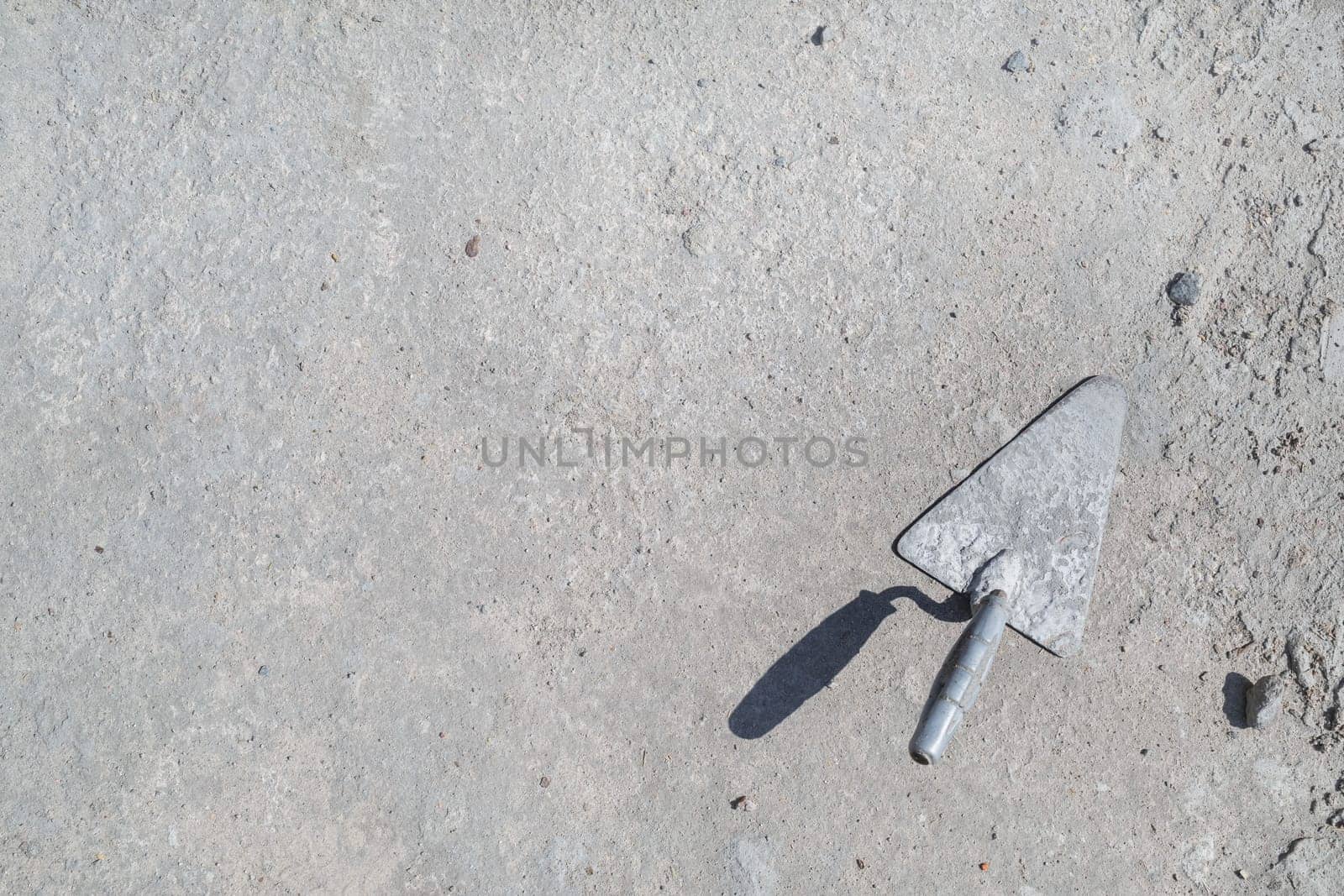 Old trowel on gray concrete background. Space for text. Flat lay.