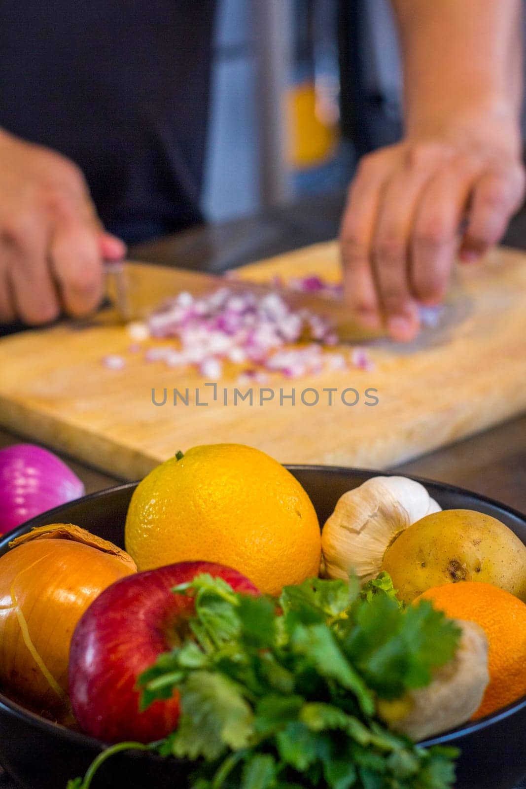 Fresh fruit in the kitchen with chef cutting onion to prepare food.